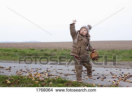 Picture - Playful girl with basket on rural road. Fotosearch