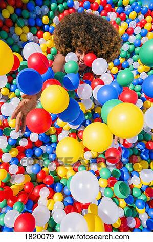 Playful young man throwing multicolor balls overhead in ball pool View Large Photo Image Stock Photo - Playful young man throwing multicolor balls overhead in ball pool. Fotosearch