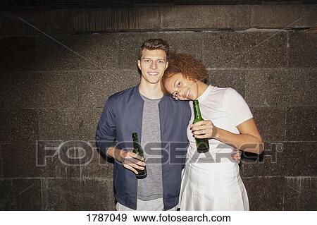 Stock Photo - Portrait affectionate young couple drinking beer. Fotosearch