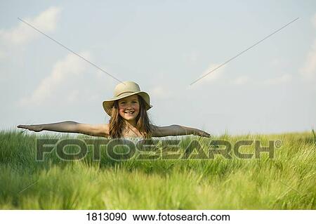 Portrait carefree girl with arms outstretched in sunny, rural green field View Large Photo Image Stock Image - Portrait carefree girl with arms outstretched in sunny, rural green field. Fotosearch