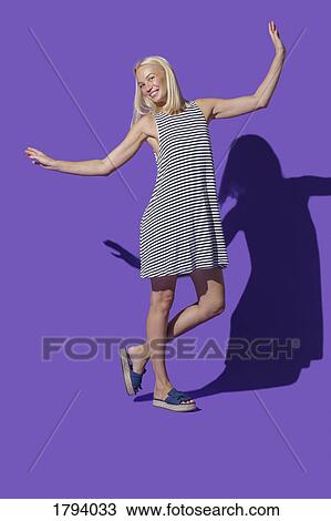 Portrait carefree woman in striped dress against purple background View Large Photo Image Stock Image - Portrait carefree woman in striped dress against purple background. Fotosearch