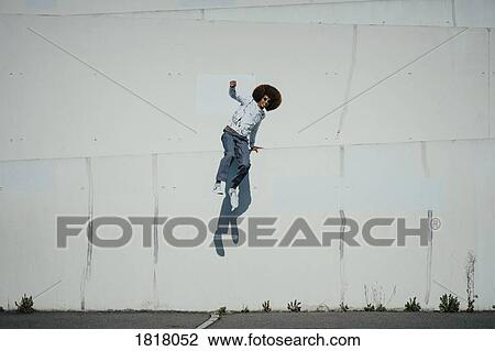 Portrait carefree young man with afro jumping at sunny wall View Large Photo Image Stock Image - Portrait carefree young man with afro jumping at sunny wall. Fotosearch