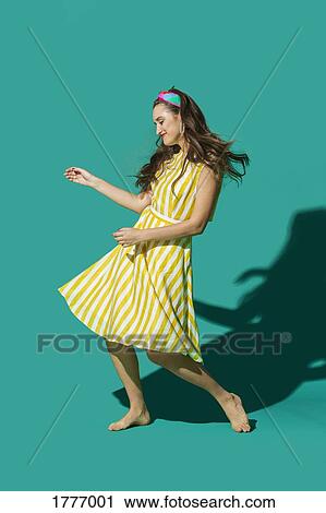 Portrait carefree young woman in striped dress dancing against turquoise background View Large Photo Image Stock Image - Portrait carefree young woman in striped dress dancing against turquoise background. Fotosearch