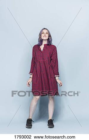 Stock Image - Portrait confident and fashionable young woman against blue background. Fotosearch