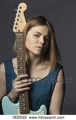 Stock Image - Portrait confident, beautiful young woman with electric guitar. Fotosearch