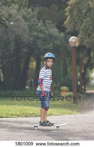 Stock Photo - Portrait confident boy skateboarding in park. Fotosearch