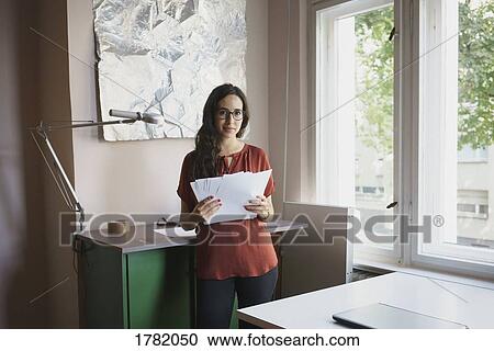 Portrait confident businesswoman with paperwork in office View Large Photo Image Stock Image - Portrait confident businesswoman with paperwork in office. Fotosearch