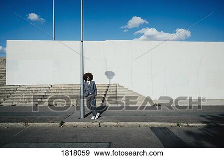 Portrait confident, cool, well-dressed young man with afro on urban sidewalk View Large Photo Image Stock Photo - Portrait confident, cool, well-dressed young man with afro on urban sidewalk. Fotosearch