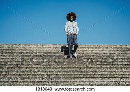 Portrait confident, cool young man with afro on sunny steps View Large Photo Image Stock Photo - Portrait confident, cool young man with afro on sunny steps. Fotosearch