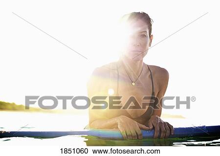 Portrait confident female surfer leaning on surfboard in sunny ocean View Large Photo Image Stock Image - Portrait confident female surfer leaning on surfboard in sunny ocean. Fotosearch