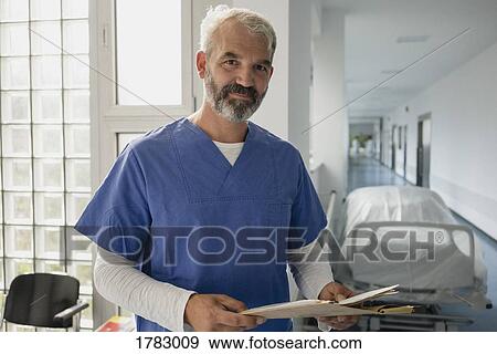 Portrait confident male doctor with medical chart in hospital corridor View Large Photo Image Stock Photo - Portrait confident male doctor with medical chart in hospital corridor. Fotosearch