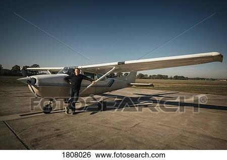 Portrait confident male pilot standing at small propellor airplane on sunny tarmac View Large Photo Image Stock Photograph - Portrait confident male pilot standing at small propellor airplane on sunny tarmac. Fotosearch