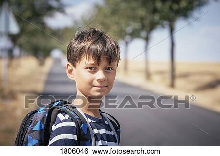 Portrait confident schoolboy with backpack on sunny road View Large Photo Image Stock Photograph - Portrait confident schoolboy with backpack on sunny road. Fotosearch