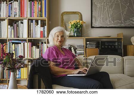 Portrait confident senior woman using laptop on living room sofa View Large Photo Image Stock Image - Portrait confident senior woman using laptop on living room sofa. Fotosearch