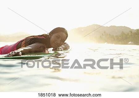 Portrait confident, serene female surfer laying on surfboard in sunny ocean View Large Photo Image Stock Photo - Portrait confident, serene female surfer laying on surfboard in sunny ocean. Fotosearch