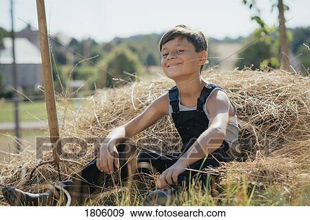 Portrait confident, smiling boy in overalls chewing on hay on sunny farm View Large Photo Image Stock Photo - Portrait confident, smiling boy in overalls chewing on hay on sunny farm. Fotosearch
