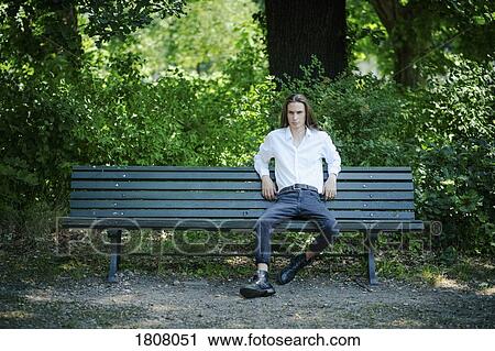 Portrait confident young man sitting on park bench View Large Photo Image Stock Image - Portrait confident young man sitting on park bench. Fotosearch