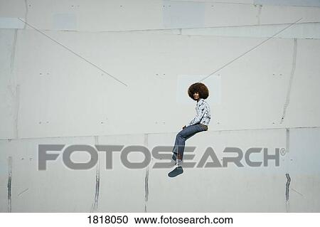 Portrait confident young man with afro sitting on sunny urban wall View Large Photo Image Stock Image - Portrait confident young man with afro sitting on sunny urban wall. Fotosearch