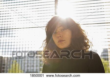 Portrait confident young woman at sunny fence View Large Photo Image Stock Image - Portrait confident young woman at sunny fence. Fotosearch