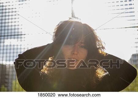 Portrait confident young woman at sunny fence View Large Photo Image Stock Image - Portrait confident young woman at sunny fence. Fotosearch