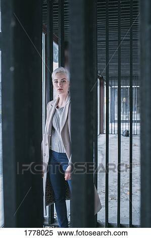 Stock Photography - Portrait confident young woman behind gate. Fotosearch