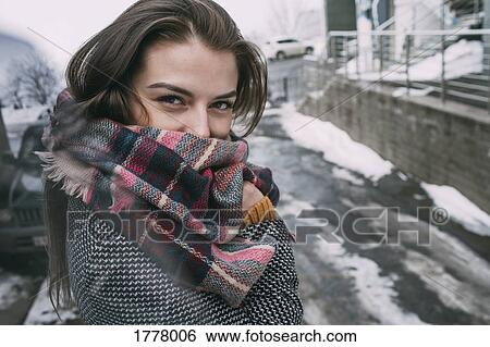 Stock Photograph - Portrait confident young woman in plaid scarf on snowy winter street. Fotosearch