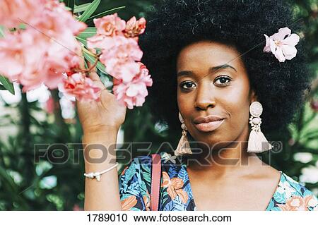 Portrait confident young woman with pink flower in hair View Large Photo Image Stock Image - Portrait confident young woman with pink flower in hair. Fotosearch