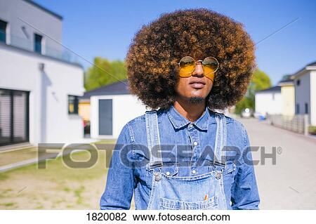 Portrait cool young man with afro in denim overalls standing on sunny road View Large Photo Image Stock Image - Portrait cool young man with afro in denim overalls standing on sunny road. Fotosearch