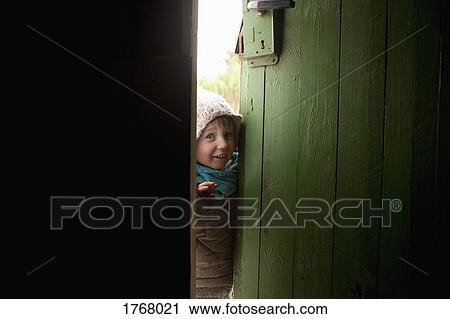 Stock Image - Portrait cute, curious girl opening door. Fotosearch