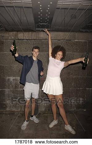 Portrait exuberant young couple drinking beer in basement View Large Photo Image Stock Photo - Portrait exuberant young couple drinking beer in basement. Fotosearch