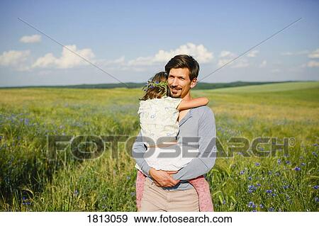 Portrait father holding daughter in sunny, idyllic rural field with wildflowers View Large Photo Image Stock Photo - Portrait father holding daughter in sunny, idyllic rural field with wildflowers. Fotosearch