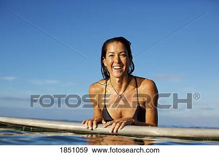 Portrait happy, confident female surfer leaning on surfboard in ocean View Large Photo Image Stock Photo - Portrait happy, confident female surfer leaning on surfboard in ocean. Fotosearch