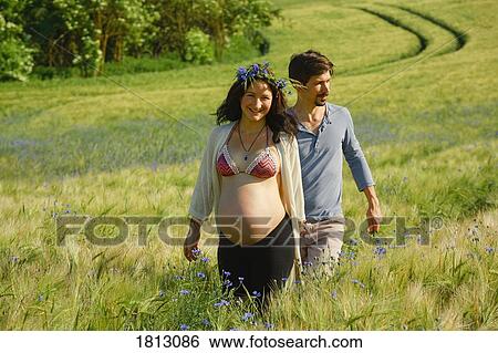 Portrait happy pregnant couple walking in sunny, idyllic rural field with wildflowers View Large Photo Image Stock Photograph - Portrait happy pregnant couple walking in sunny, idyllic rural field with wildflowers. Fotosearch