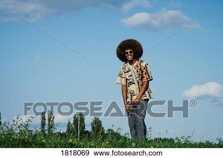 Stock Photo - Portrait happy young man with afro in park grass. Fotosearch