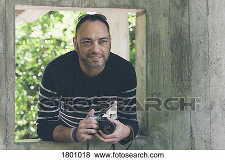Portrait man with camera standing in garden window View Large Photo Image Stock Photo - Portrait man with camera standing in garden window. Fotosearch