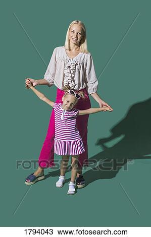 Portrait mother and daughter holding hands against green background View Large Photo Image Stock Image - Portrait mother and daughter holding hands against green background. Fotosearch