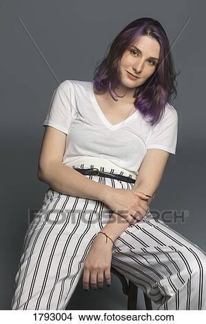 Portrait of a confident young woman sitting on a chair View Large Photo Image Picture - Portrait of a confident young woman sitting on a chair. Fotosearch