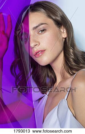 Stock Image - Portrait of a female fashion model posing with purple plastic sheet. Fotosearch