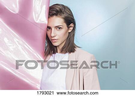 Stock Image - Portrait of a female fashion model posing with pink fabric. Fotosearch