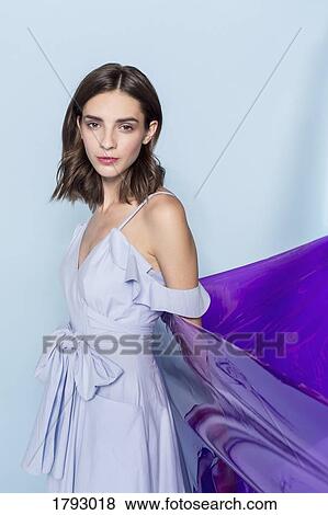 Stock Photo - Portrait of a female fashion model posing with purple plastic sheet against blue background. Fotosearch