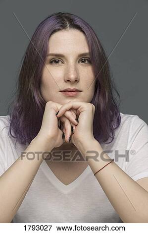 Portrait of a young woman with dyed hair and resting chin on hands against gray background View Large Photo Image Stock Photo - Portrait of a young woman with dyed hair and resting chin on hands against gray background. Fotosearch