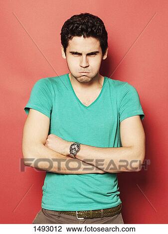 Portrait of angry young man with puffed cheeks standing arms crossed against red background View Large Photo Image Stock Image - Portrait of angry young man with puffed cheeks standing arms crossed against red background. Fotosearch