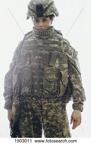 Stock Image - Portrait of army soldier carrying rifle standing against white background. Fotosearch