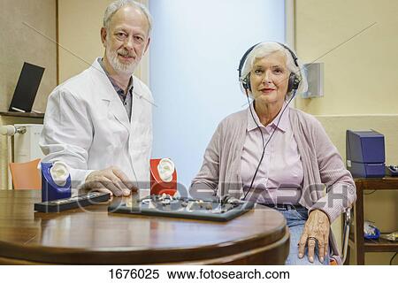 Portrait of audiologist and senior patient wearing headphones during ear exam at clinic View Large Photo Image Stock Photography - Portrait of audiologist and senior patient wearing headphones during ear exam at clinic. Fotosearch