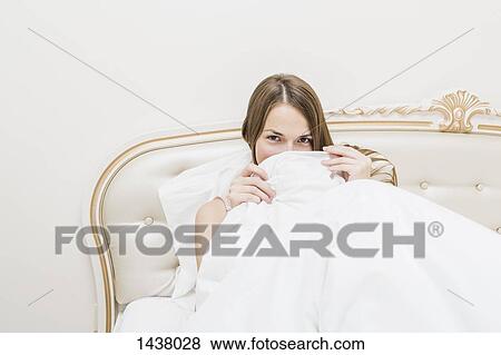 Portrait of beautiful woman hiding in duvet at home View Large Photo Image Stock Photo - Portrait of beautiful woman hiding in duvet at home. Fotosearch