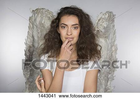 Stock Image - Portrait of beautiful woman in angel wings against gray background. Fotosearch