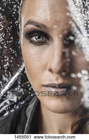 Stock Image - Portrait of beautiful woman in plastic against black background. Fotosearch