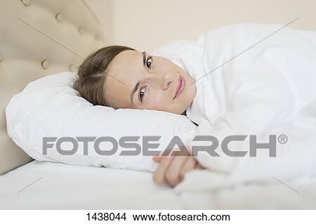 Picture - Portrait of beautiful woman relaxing in bed at home. Fotosearch
