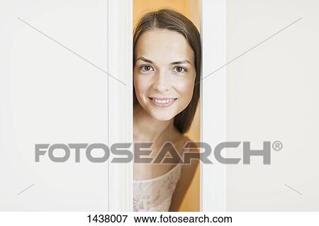 Portrait of beautiful woman smiling while peeking through doors View Large Photo Image Stock Photo - Portrait of beautiful woman smiling while peeking through doors. Fotosearch