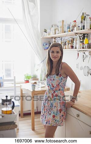 Portrait of beautiful woman standing by counter in kitchen at home View Large Photo Image Stock Photograph - Portrait of beautiful woman standing by counter in kitchen at home. Fotosearch